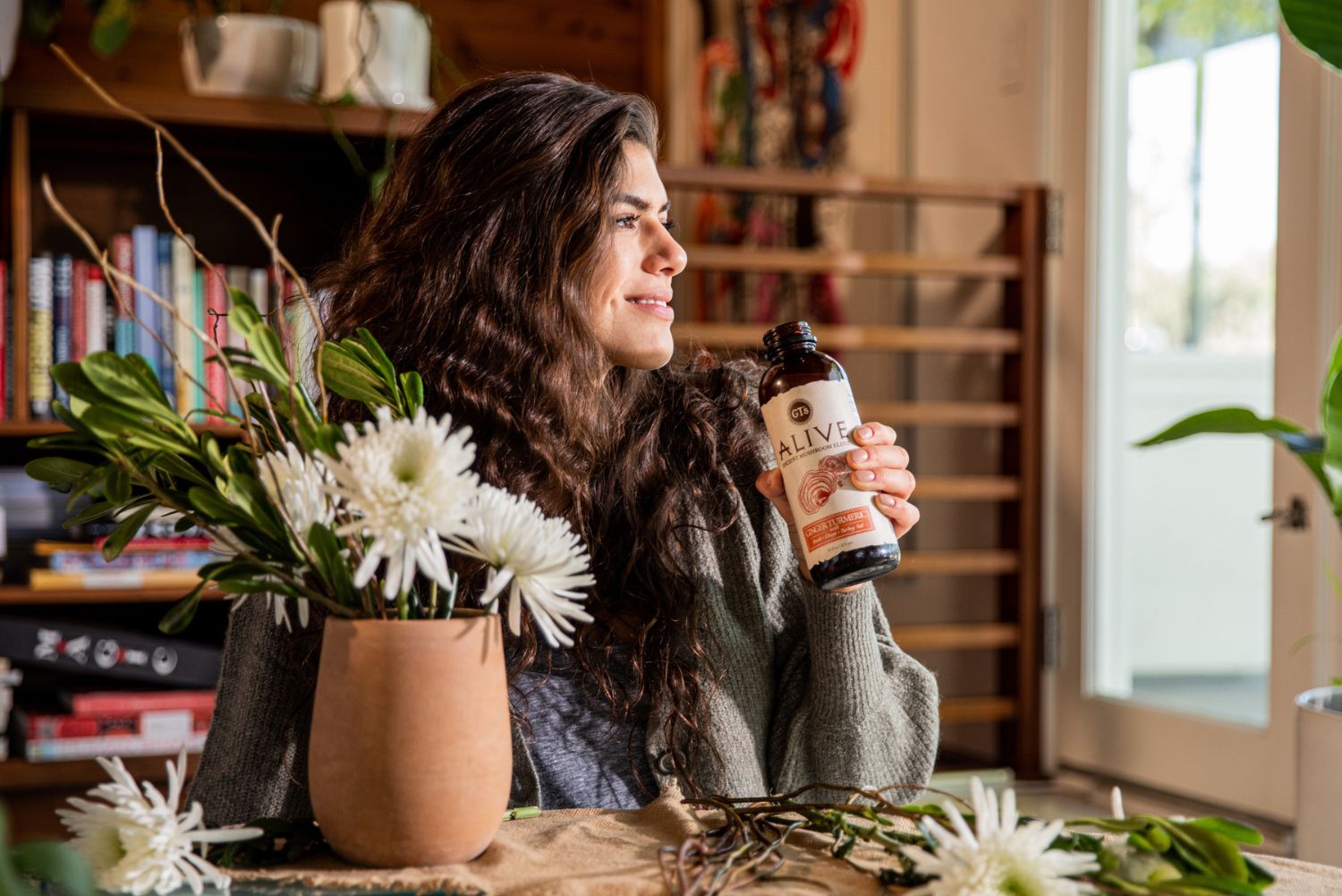 Person drinking GT's ALIVE Ancient Mushroom Elixir looking out window